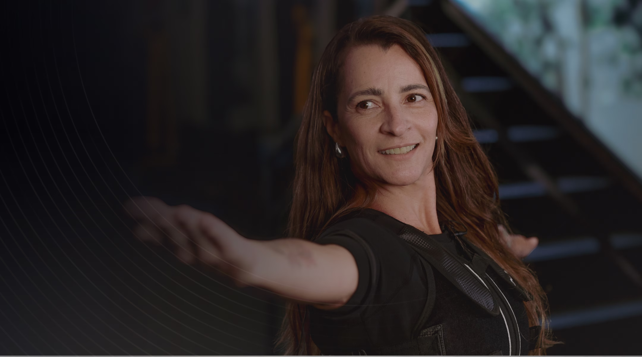 Aluna sorridente durante sessão de eletroestimulação Tecfit, vestindo o traje EMS completo