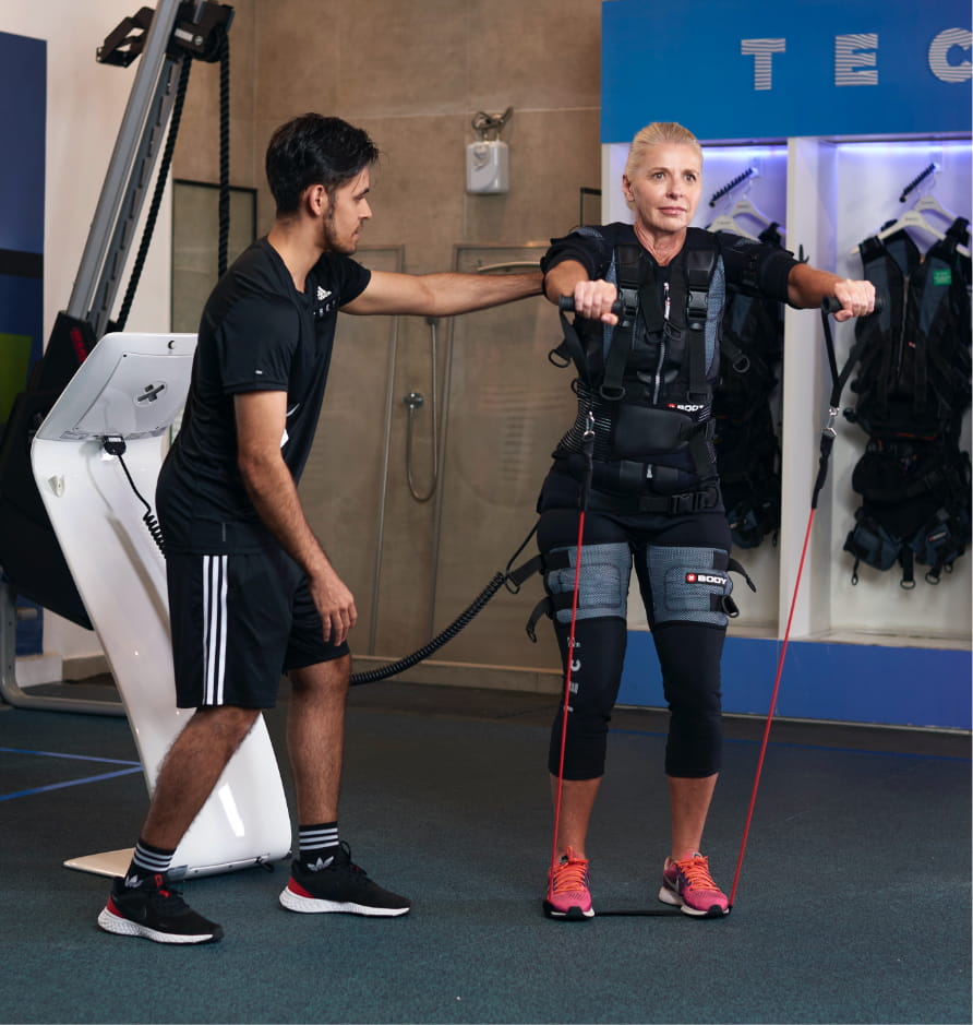 Especialista Tecfit supervisionando aluna durante exercício de resistência com o traje EMS