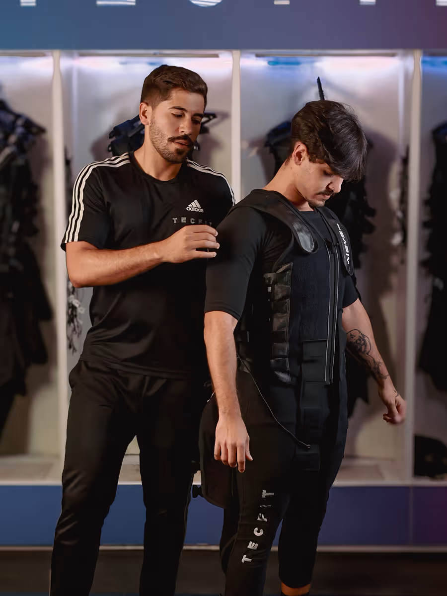 Especialista Tecfit ajustando o traje de eletroestimulação em uma aluna antes da sessão